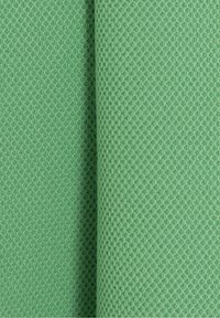 Närbild av vikt mintgrön våffelstickad tyg som visar den texturerade mönstret och det mjuka materialet.