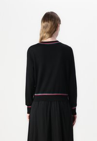 Black sweater featuring long sleeves, a round neckline, and multicolored trim at the collar and hem, made from a soft knit material.