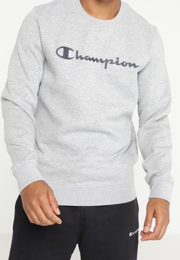 Sudadera grigia con scollatura rotonda, maniche lunghe e un grande logo "Champion" in blu navy sul petto. Materiale morbido in misto cotone.