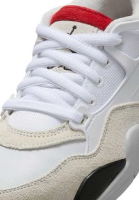 Zapatilla blanca que combina varios materiales, incluyendo cuero suave y ante. Acentos rojos en la lengüeta y cordones blancos. Detalles de diseño texturizado.