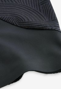 Schwarzer Stoff mit glatter Textur und einer gemusterten oberen Schicht, die dezente gekrümmte Linien aufweist, die über einem undurchsichtigen schwarzen Grundmaterial liegt.