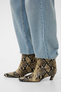 Jean bleu clair associé à des bottines à bout pointu avec un motif en peau de serpent beige et noir et de petits talons.