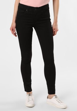 Los pantalones vaqueros ajustados negros, fabricados con tejido elástico, cuentan con un diseño clásico de cinco bolsillos y están diseñados con una cintura de altura media para un ajuste ceñido.