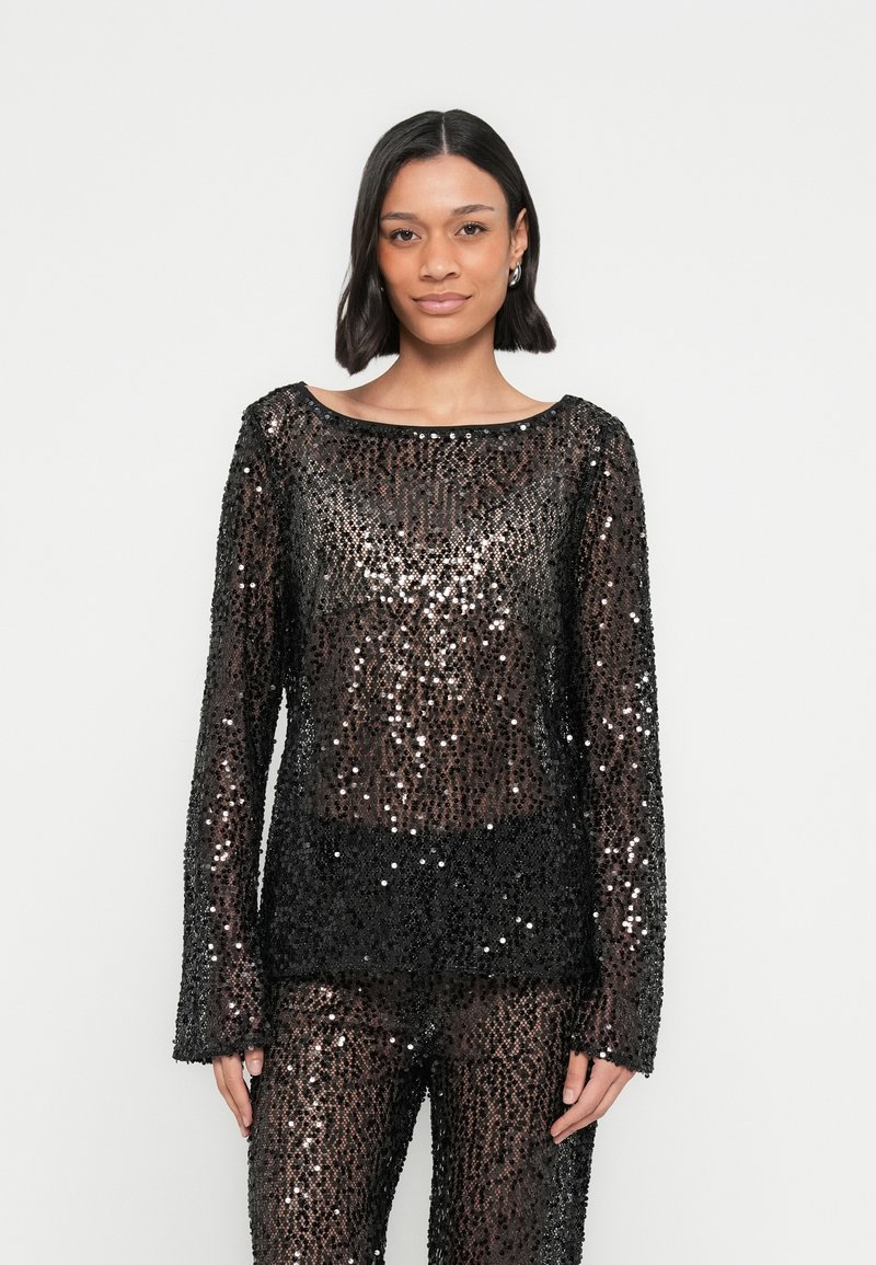 Črna majica z dolgimi rokavi iz bleščečih sequins z širokim izrezom in prozornim dizajnom, ki omogoča vpogled v spodnjo plast.