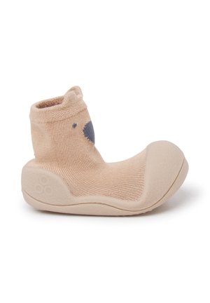 Beżowe skarpetkowe buty z miękką gumową podeszwą. Teksturowany materiał dzianinowy z zaokrąglonym noskiem. Szary wzór twarzy misia z przodu.