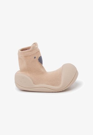 Beige sock shoe with a soft rubber sole. Textured knit material featuring a rounded toe. Gray bear face design on the front.