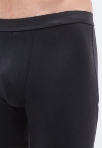 Juodi medvilniniai bokseriai su lygiu audiniu, elastinga liemene ir siūlių detalėmis priekyje bei šonuose.