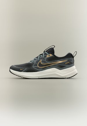 Pantof de alergare Nike negru și gri cu logo swoosh auriu, talpă albă amortizată și curelușe pentru tras pe limbă și călcâi, vedere laterală pe fundal simplu.