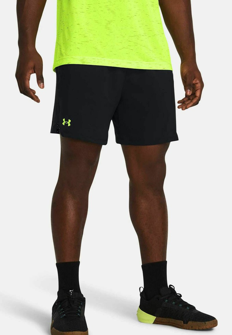 Pantaloni sportivi neri realizzati in tessuto leggero, con il logo verde di Under Armour. Abbinati a calze nere e scarpe da ginnastica con dettagli verdi.