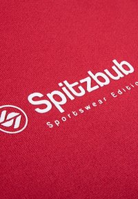 Rode textiel met een gladde textuur, voorzien van een wit geborduurd logo: "Spitzbub Sportswear Edition" naast een cirkelvormig embleem.