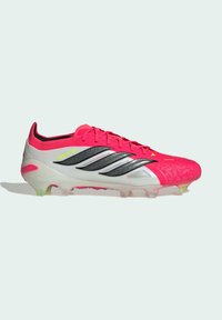 Κόκκινο και λευκό ποδοσφαιρικό παπούτσι Adidas Predator με μαύρες ρίγες, κορδόνια και ημιδιαφανείς αγκράφες σε φωτεινό φόντο.