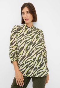Lange mouwblouse van lichtgewicht stof met een groen en bruin zebrapatroon, voorzien van een hoge halslijn en geplooide mouwmanchetten.