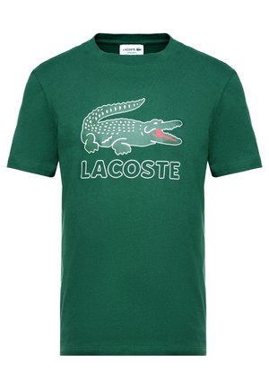 T-shirt en coton vert avec un grand crocodile blanc imprimé et le texte "LACOSTE" en blanc en dessous. Conception classique à col rond avec manches courtes.