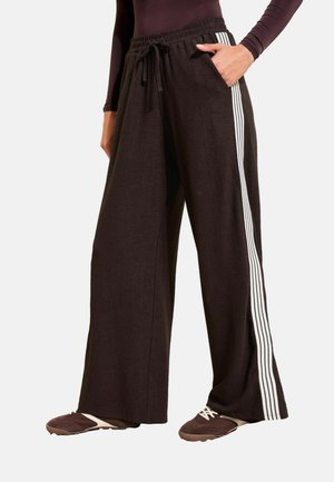 Schwarze weite Hosen aus strukturiertem Stoff mit einem Kordelzug am Bund und weißen Streifen an den Seiten. Taschen vorhanden.