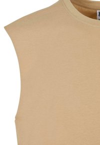 Beige mouwloos T-shirt met een ronde hals, gemaakt van zacht katoen. Heeft gedefinieerde schouders en een gladde, egale textuur.