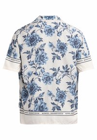 Korte mouw shirt met blauwe bloemmotieven en kleine stippen op witte achtergrond, met de tekst "REBEL REDEFINED" op de mouwen en de zoom.