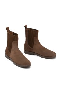 Botine din suede maro, cu panouri din țesătură ribbată, tălpi plate și cârlige de prindere. Textură netedă cu un design cu vârf rotunjit.