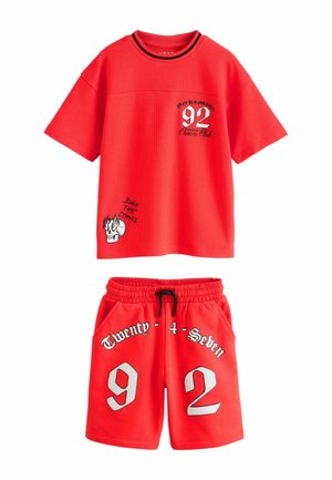 Červená súprava z krátkym rukávom a krátkymi nohavicami s textom "92" a "Twenty-4-Seven", grafikou lebky a čiernou šnúrkou na elastickom páse šortiek.