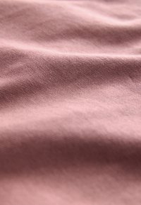 Woven textile in soft pink, featuring a smooth texture with subtle geometric patterns and lightweight, flexible material.