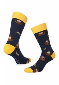 Granatowe skarpetki z żółtymi palcami, piętami i mankietami, zdobione rozproszonymi wizerunkami kreskówkowych twarzy małp i ilustracjami bananów.