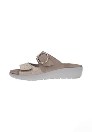 Sandalia beige de tiras abiertas con suela blanca de plataforma, tira frontal ajustable con velcro y hebilla decorativa con piedras brillantes en la tira superior.