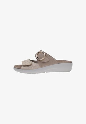 Sandalia beige de tiras abiertas con suela blanca de plataforma, tira frontal ajustable con velcro y hebilla decorativa con piedras brillantes en la tira superior.