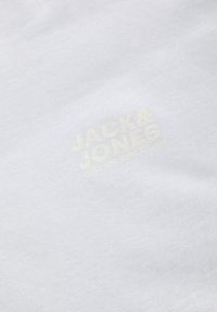 Witte katoenen t-shirt met een gladde textuur, featuring een gele bedrukte logo "JACK & JONES" samen met "CORE NINE ZERO EST. 1990."