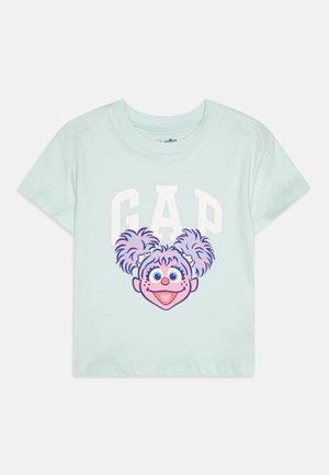 Mint green cotton t-shirt featuring a graphic of a character's head with purple and pink pigtails, and 'GAP' text in white above.