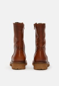 Stivaletti in pelle marrone con finitura liscia, cerniera sul retro e suola in gomma texturizzata. Presentano un marchio discreto sul tallone.