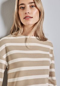 Beige und weiß gestreiftes Strickoberteil mit einem Boot-Ausschnitt und lockerer Passform, aus strukturiertem Stoff und mit lässigen Ärmeln.