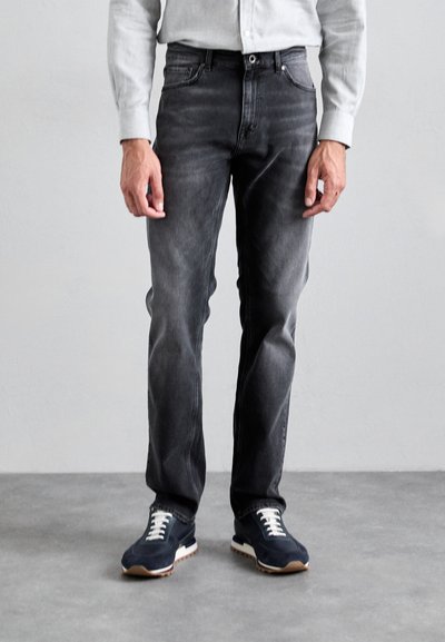 Gray denim jeans with a slim fit, five-pocket design, subtle fading, and a mid-rise waist, paired with navy sneakers and a light button-up shirt.