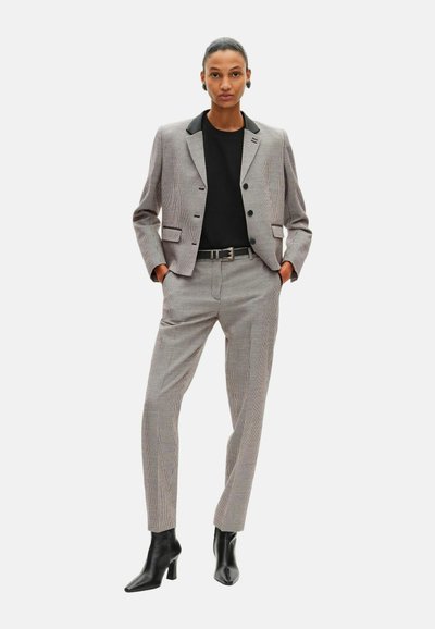 Structured gray houndstooth blazer with black lapels, paired with tailored pants and black high-heeled boots. Minimalist design, fitted shape.