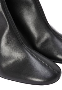 Bottes chevilles en cuir noir avec un bout pointu, une texture lisse, et des coutures minimales visibles le long des bords.
