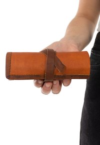 Brown leather roll-up case with a smooth texture, secured by a dark brown leather strap, featuring visible stitching along the edges.
