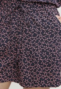 Námořnické šortky s páskem na stažení, s růžovým vzorem hvězd. Materiál je lehký s hladkým povrchem a obsahuje boční kapsu.