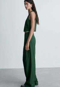 Top court vert et pantalon large taille haute, tous deux ornés de rayures blanches verticales. Tissu lisse avec une coupe structurée.