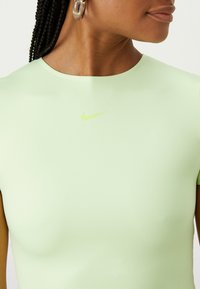 Ljusgrön atletisk topp med korta ärmar, med en liten klargrön Nike-logga på bröstet, slät textur och figurnära design.