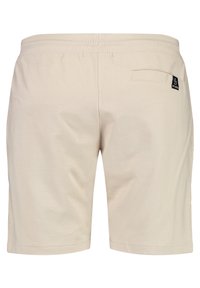 Beige Shorts mit glatter Textur. Elastischer Bund, Gesäßtasche und kleines Logoetikett auf der rechten Seite. Einfaches, gerades Design.