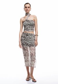 Twee-delig leopardprint outfit met een aansluitende, strapless top en een doorschijnende, gerimpelde midi rok. Kleuren zijn lichtgrijs, bruin en zwart.