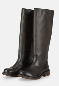 Botas de cuero negras altas con un acabado brillante, punta redondeada y cremallera lateral. Superficie texturizada con un contraste marrón rústico cerca de la suela.