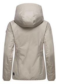 Beige waterproof jacket with a hood, elastic cuffs, and subtle texture; features a logo patch on the left side near the hem.