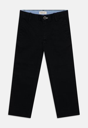 Chinos en coton noir avec une texture lisse, coupe slim, passants pour ceinture et fermeture par bouton. Détail intérieur de la ceinture en bleu clair.