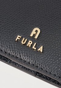 Black leather wallet featuring a textured surface with gold hardware. The logo "FURLA" is prominently embossed in gold lettering.