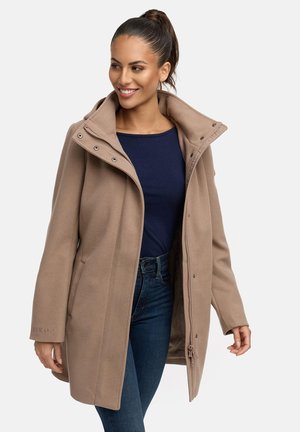 Manteau en mélange de laine beige avec fermeture éclair et à pression, grand col, et poches latérales, porté sur un haut marine et associé à un jean bleu.
