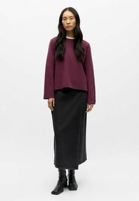 Burgunderrød sweatshirt med rund halsudskæring, parret med en sort denim maxi nederdel og knæhøje sorte hælede støvler. Minimalistisk design.