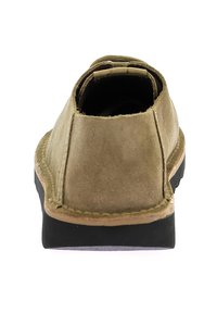 Zapato de ante con parte trasera redondeada, color beige, suela negra contrastante y costuras visibles a lo largo del borde. Diseño simple y práctico.