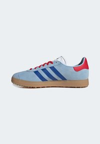 Baskets en suède bleu avec des lacets rouges, trois rayures bleues sur les côtés, une semelle en caoutchouc gomme et un talon rembourré avec des accents rouges et bleu clair.