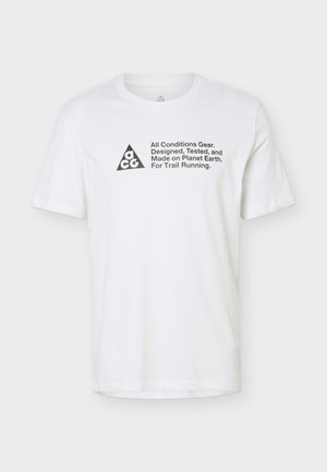 Biały T-shirt z krótkim rękawem z czarnym trójkątnym logo "ACG" i tekstem: "All Conditions Gear. Designed, Tested, and Made on Planet Earth. For Trail Running."