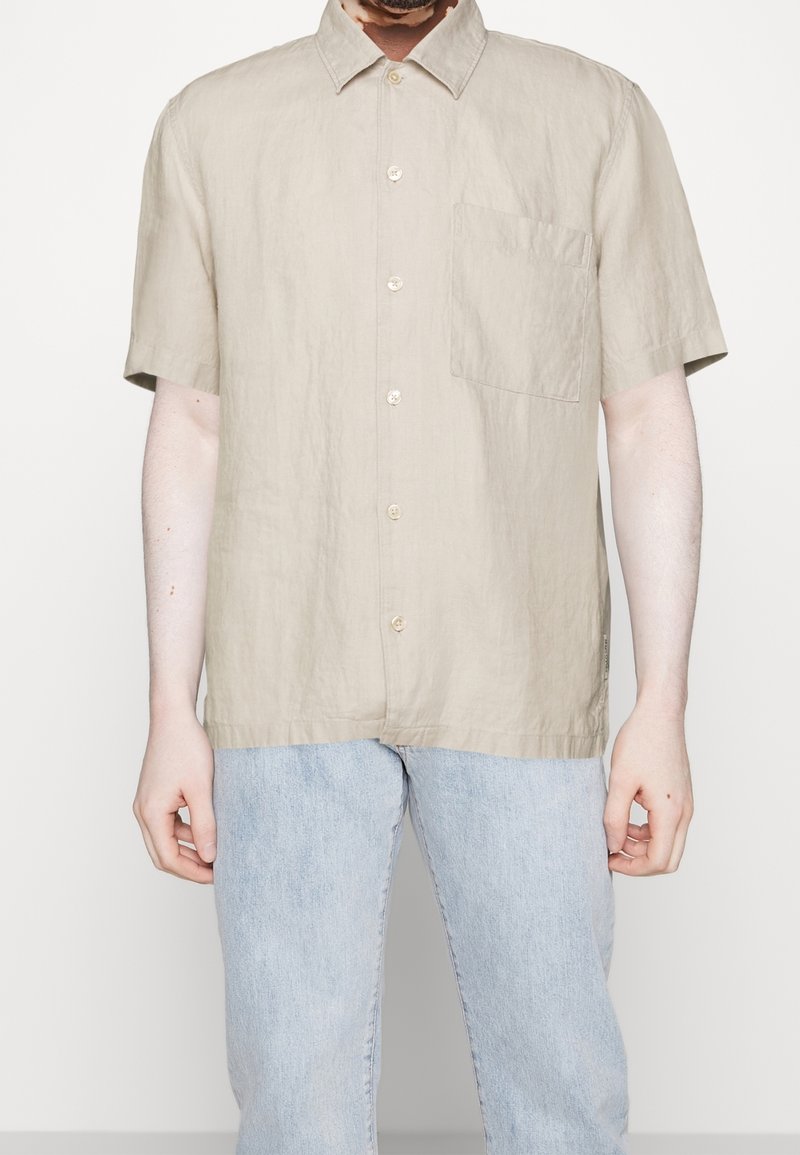 Ljusbeige kortärmad skjorta i en linneblandning med knäppning framtill, en enkel bröstficka och en avslappnad passform.