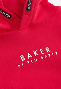Sudadera de algodón roja con un bolsillo frontal, capucha con cordones y letras blancas que dicen "BAKER BY TED BAKER" en el pecho.